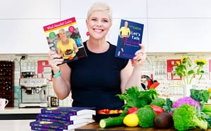 Photo of Annabel Bateman in her kitchen holding her 2 books What annabel cooks and Let's Talk Thyroid